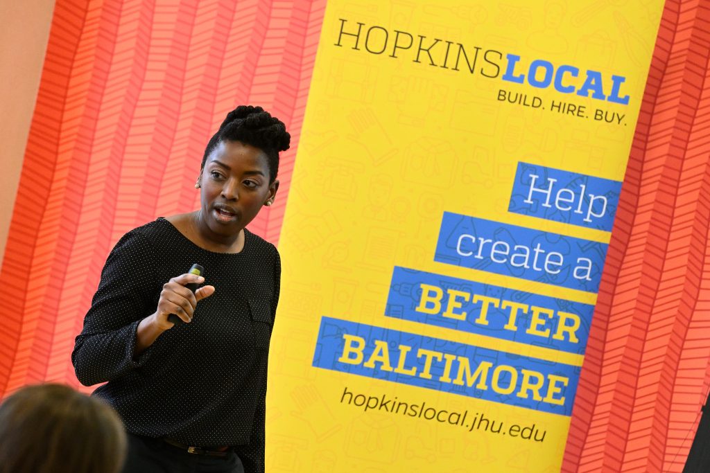 Speaker talking in front of a Hopkins Local sign