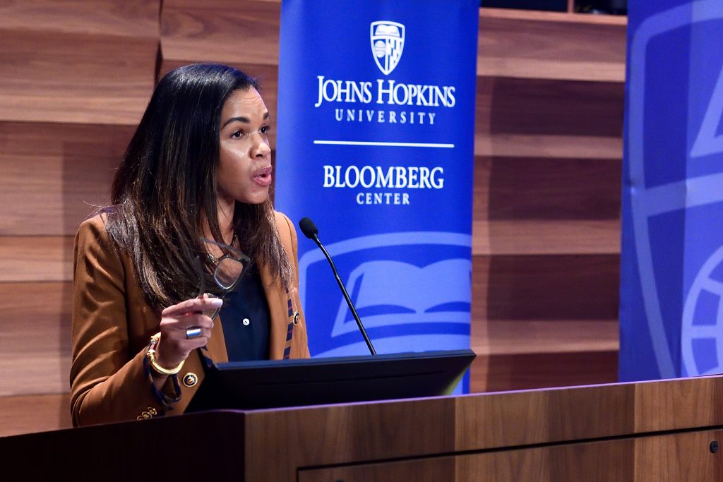 Female speaker at podium with branded vertical pull-up banners in the background