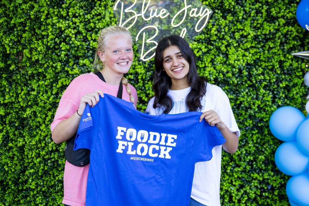 Two students holding up a Foodie Flock t-shirt