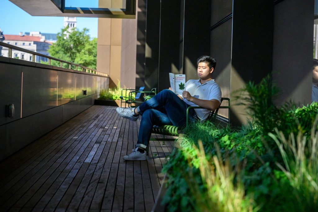 Student reading on the outdoor balcony spaceat the Hopkins Bloomberg Center in Washington, D.C.