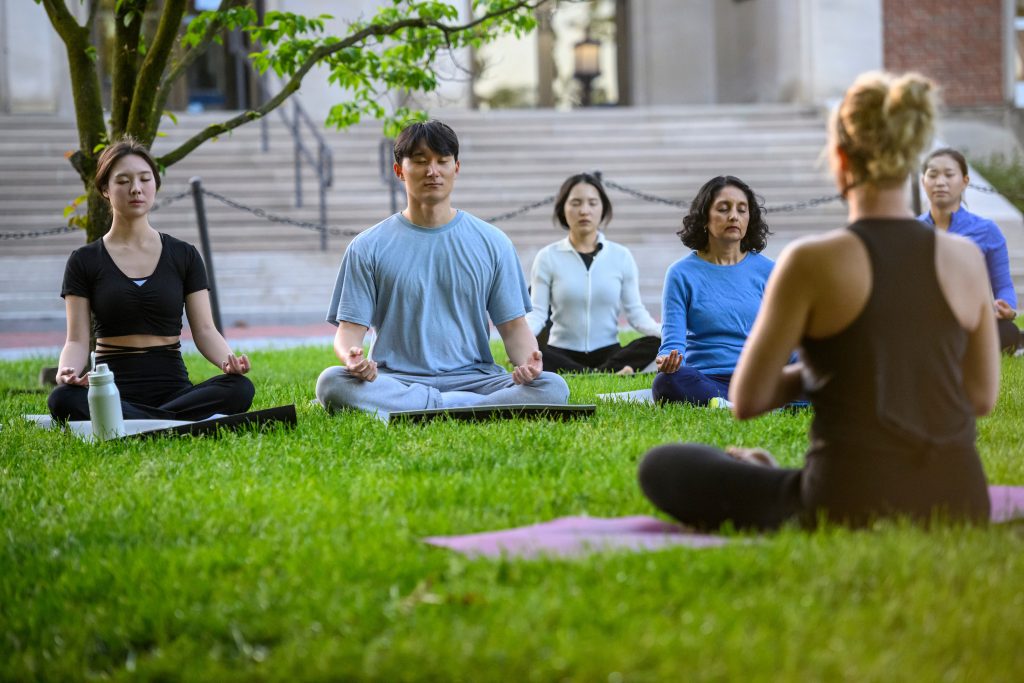 Students participating in yoga class on the lawn of Homewood Campus