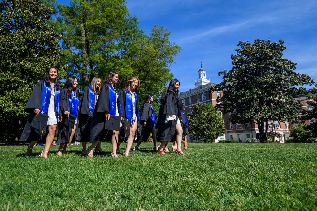 Graduates walking across the quad in their cap and gowns