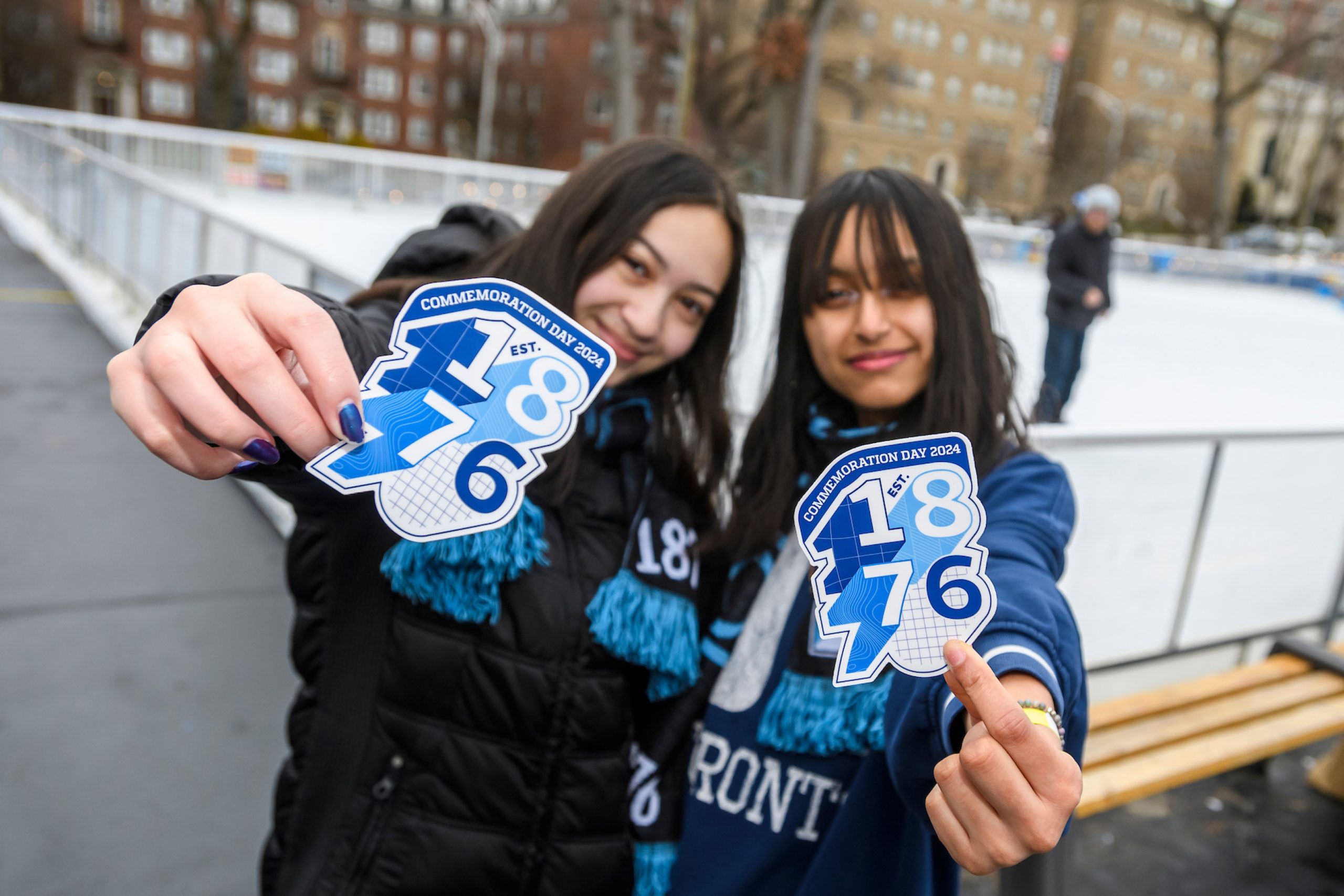 Two students holding Commemoration Day sticker at ice rink