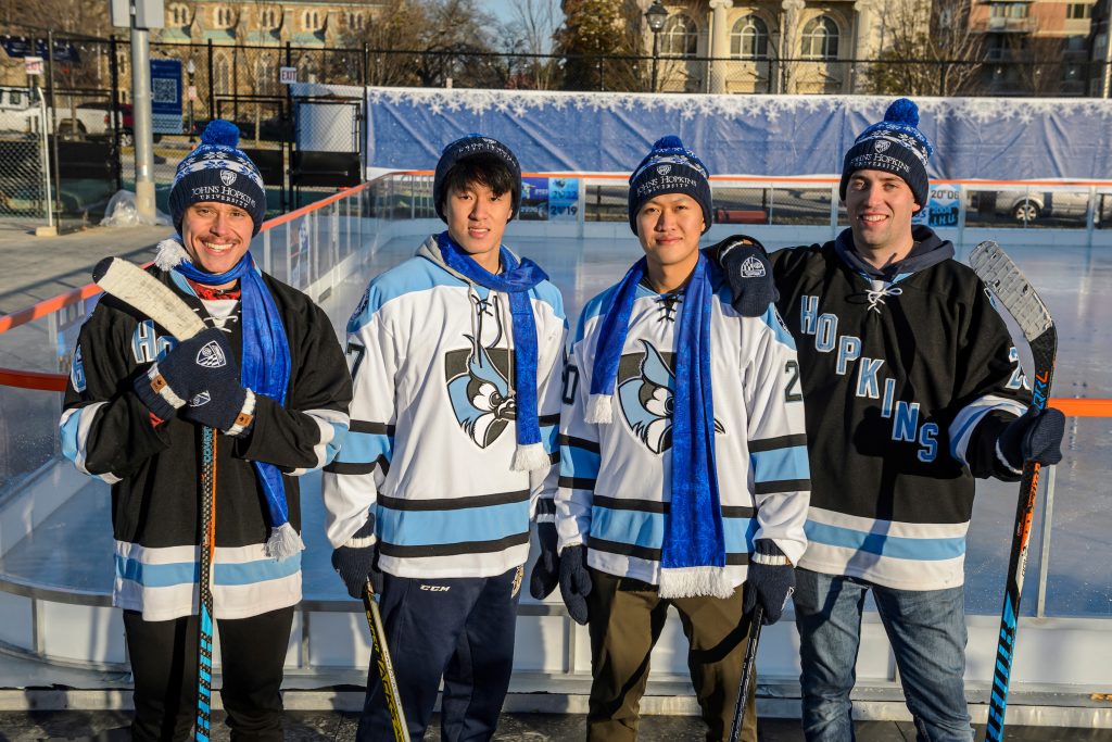 Hockey players wearing Hopkins jerseys and merchandise in front of the pop-up ice rink