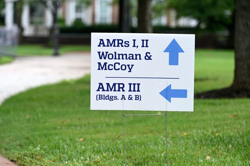 Lawn sign featuring building names and arrows