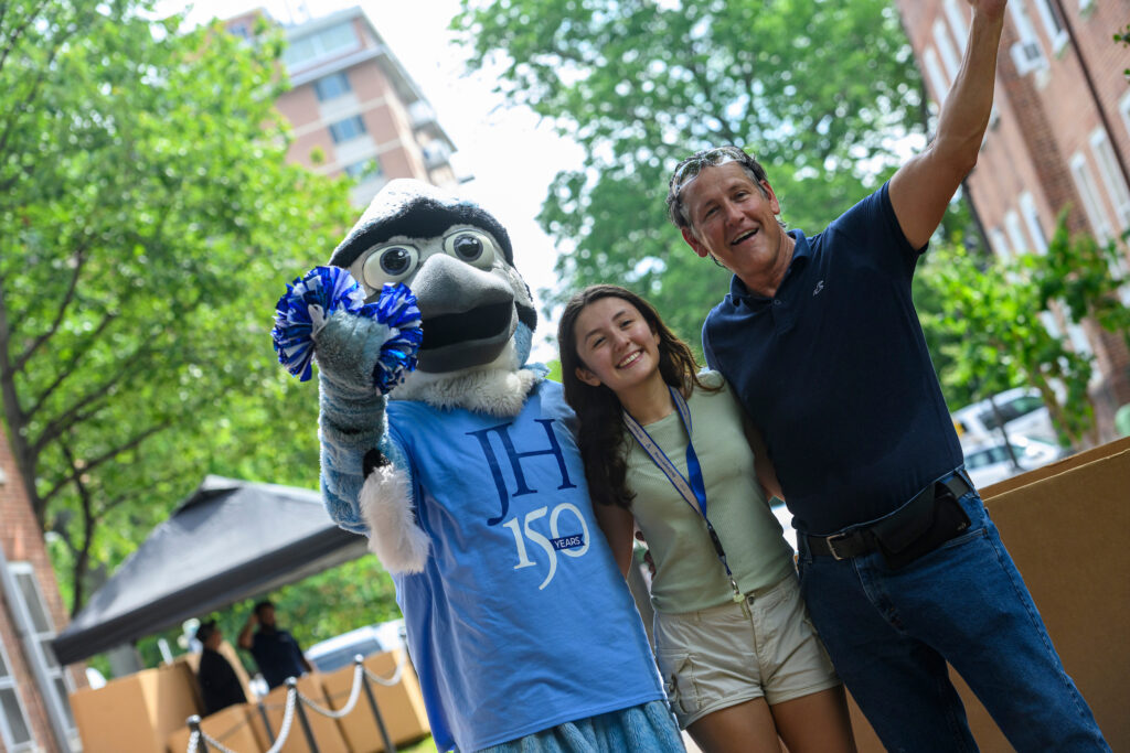 Jay mascot wearing a JH150 shirt and posing with new student and dad